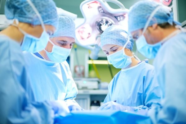 Team of surgeons operating patient in operating room at hospital. Horizontal shot.